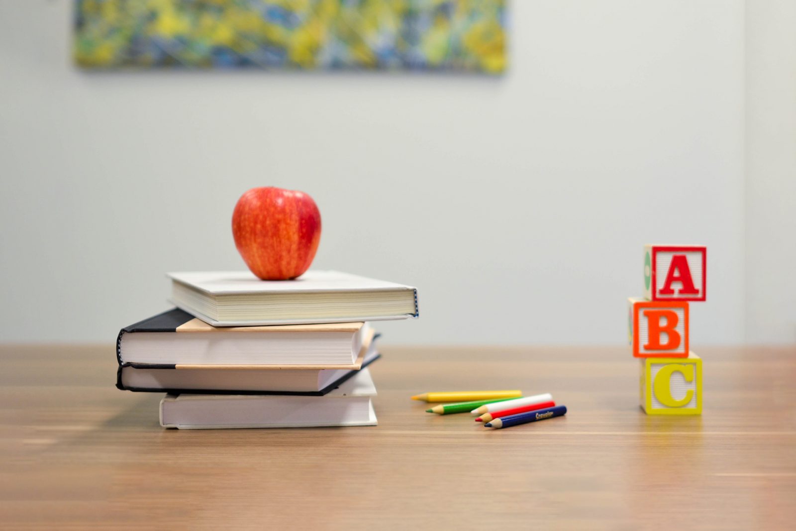Pöydällä kirjoja pinossa ja omena