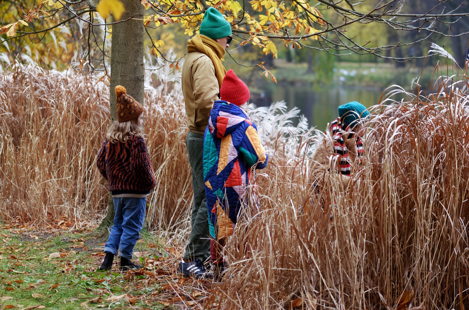 Mies ja kolme lasta syksyllä järven rannassa