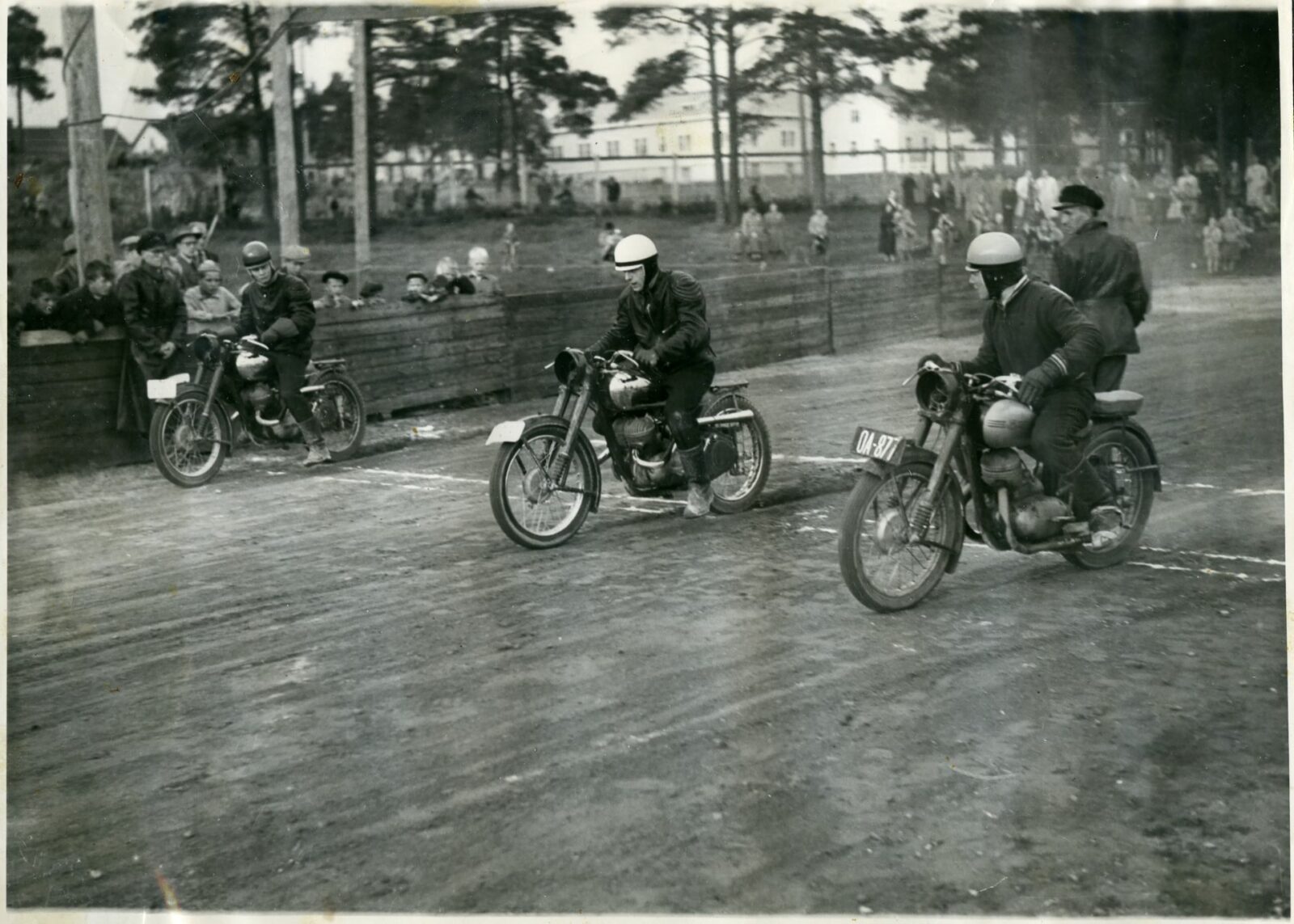 Vanha mustavalkoinen valokuva, jossa kaksi miestä ajaa mopoilla